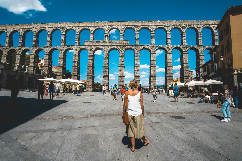 Explore the iconic Roman aqueduct in Segovia, a UNESCO World Heritage site, bustling with tourists.